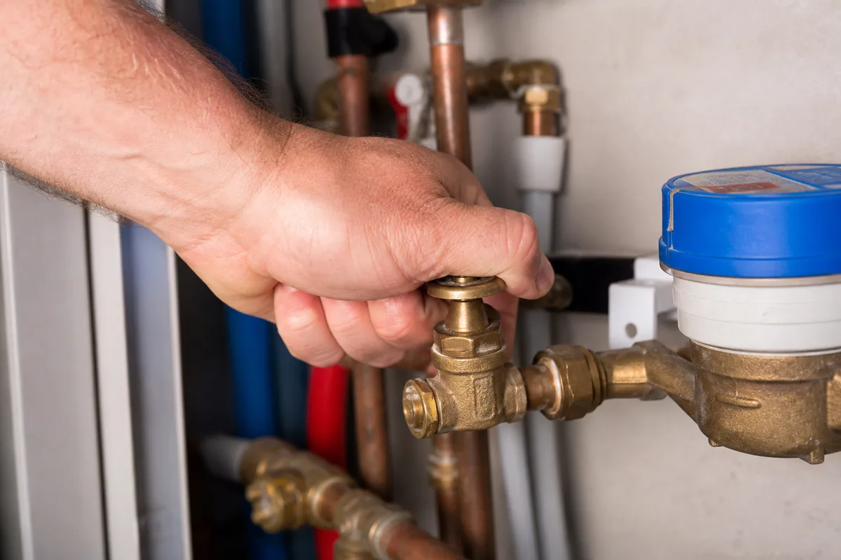 Vanne d&rsquo;arrêt générale d&rsquo;eau fermée à la main près d&rsquo;un compteur dans un logement